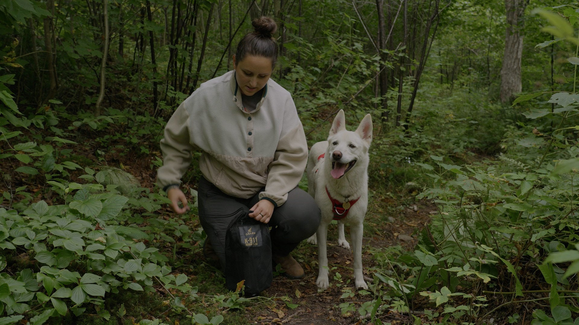 Woman with her dog installing the Rescue Sling with the Ascension Extended harness in the forest