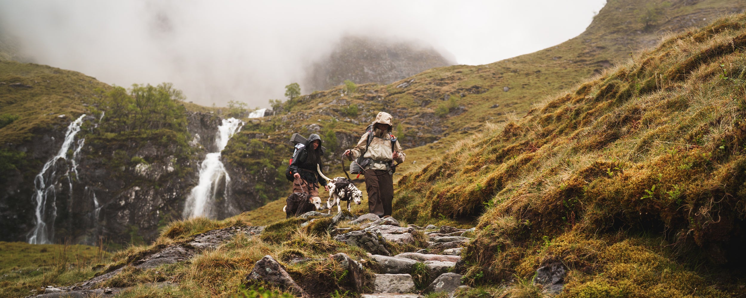 Couple hiking in scotland with their dogs wearing the Säker espresso collection