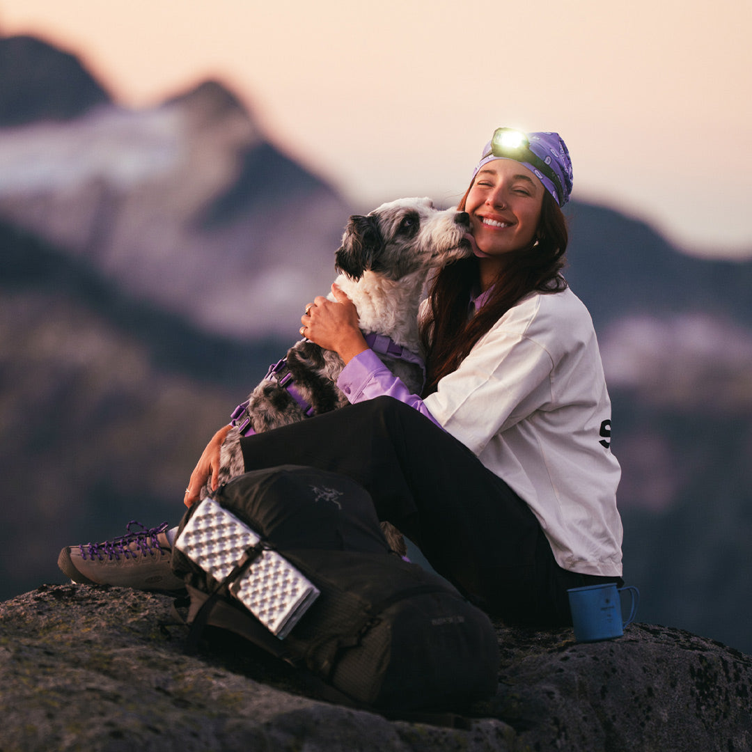 Woman and her dog kissing in Squamish wearing the Muse harness in Lilas at the summit of a hike