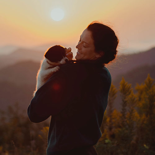 Woman carrying her new puppy at sunrise