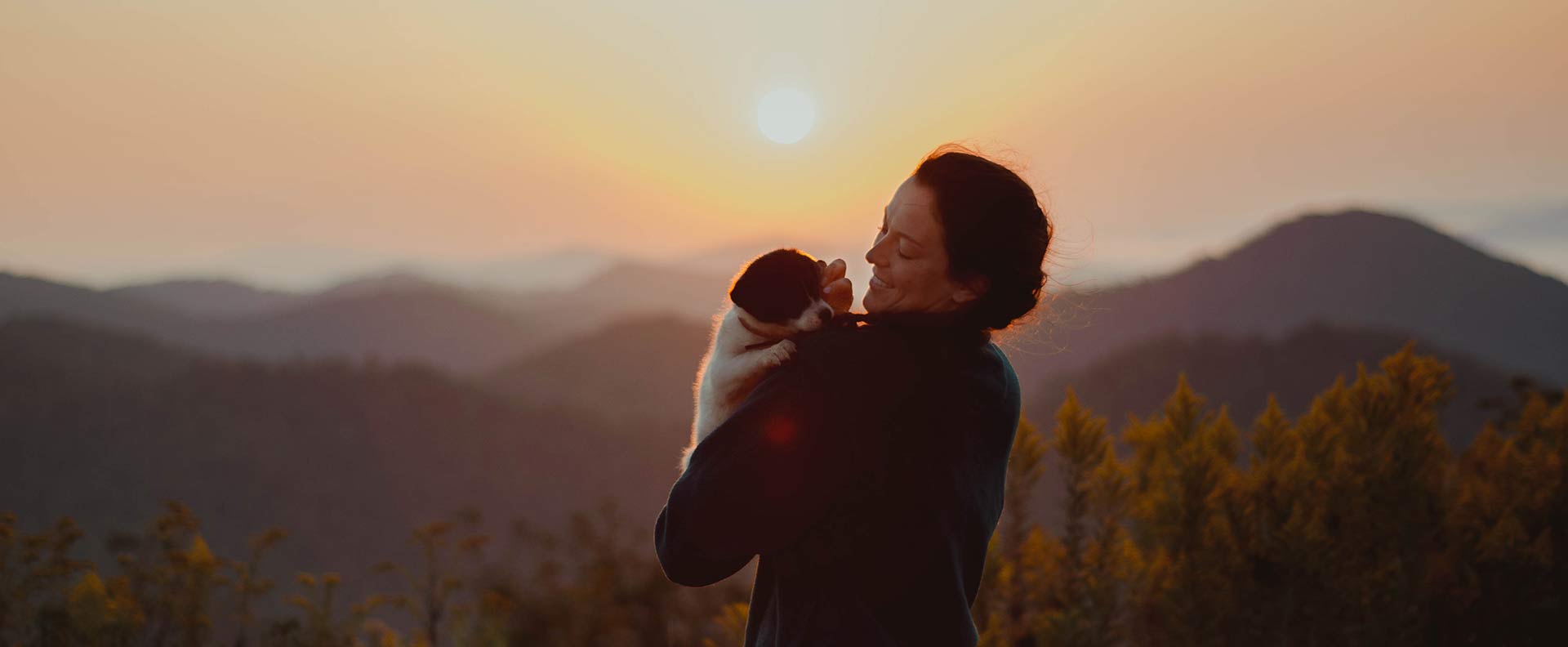 Woman carrying her new puppy at sunrise