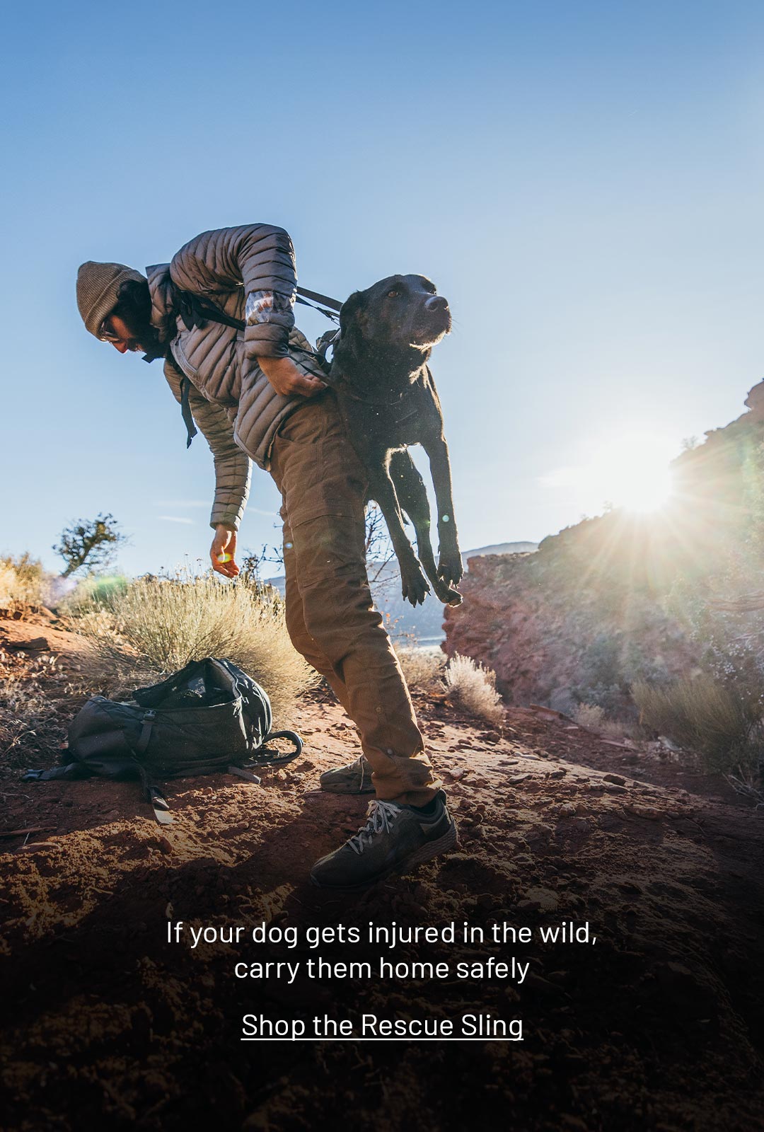 Man lifting his injured dog with the K-911 Rescue Sling in the desert