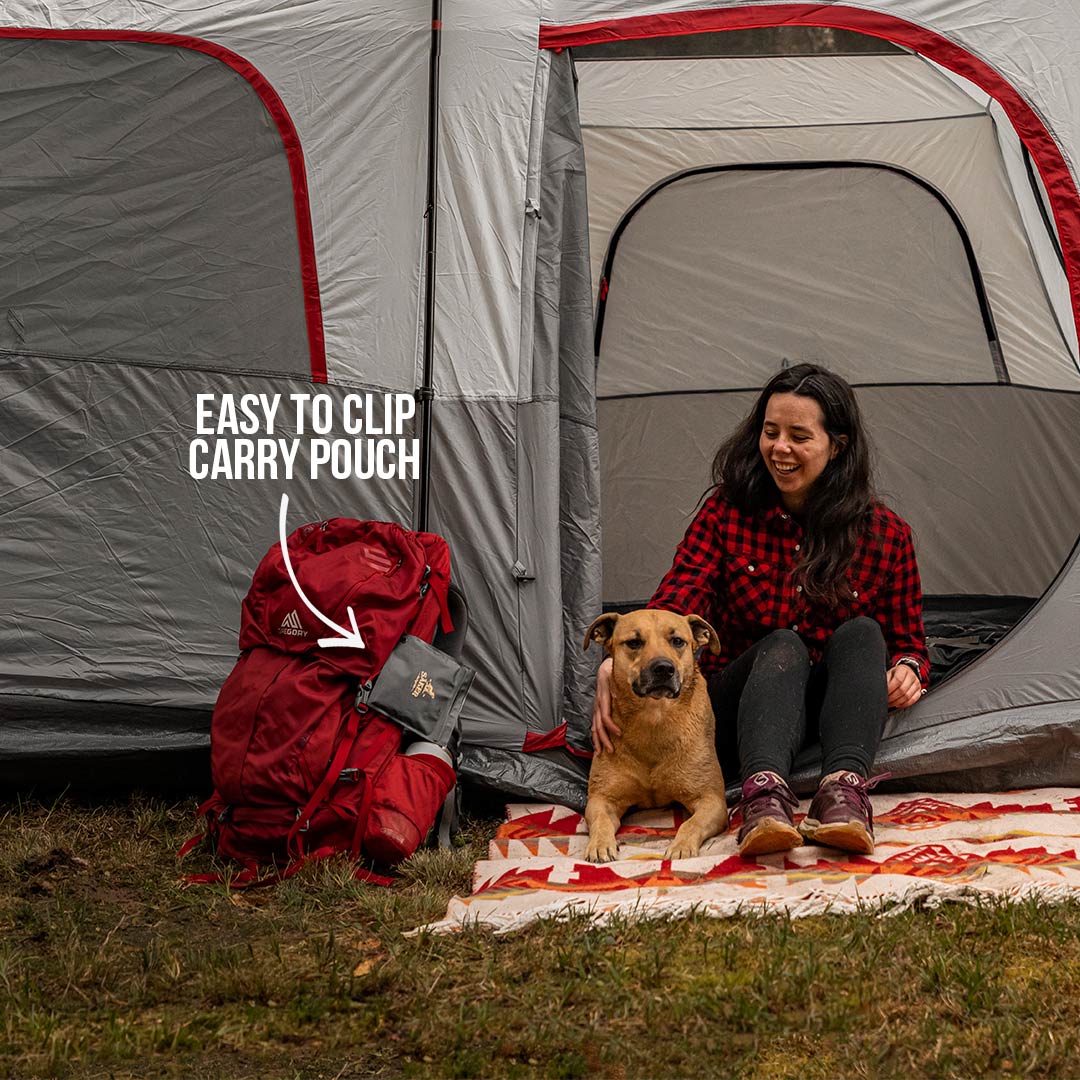 dog mom in her tent with her dog and the tick buster is attached to a backpack next to them