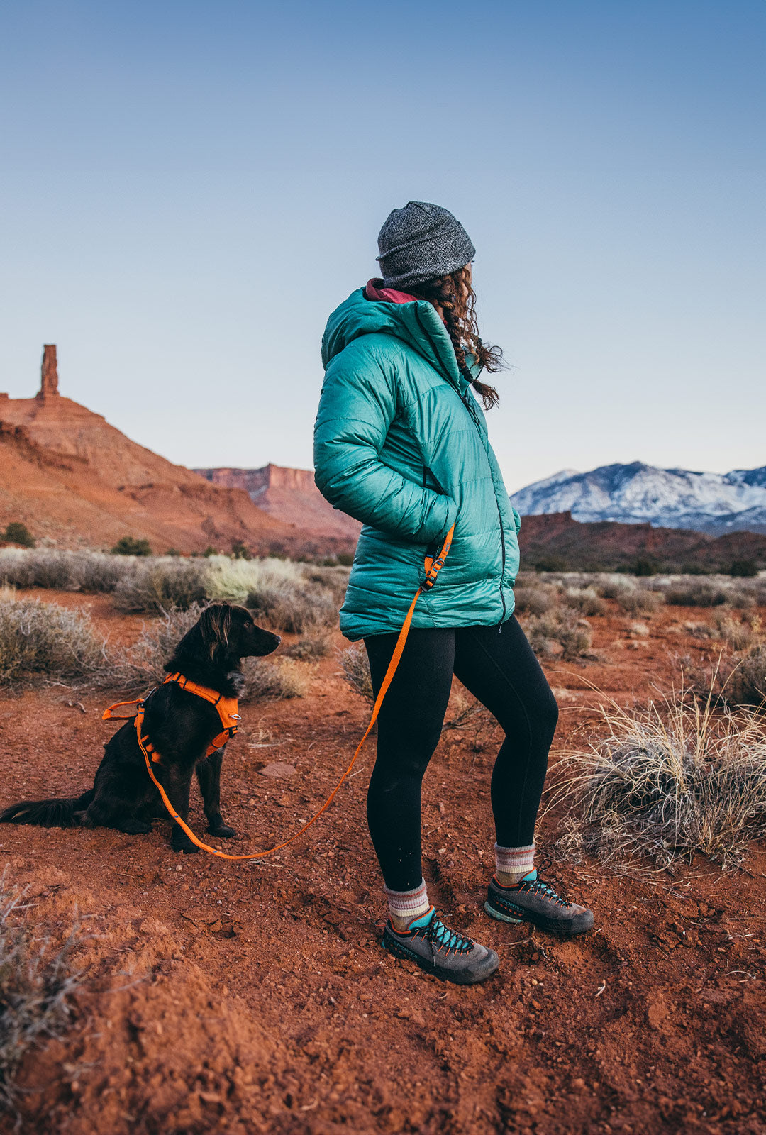 woman standing in the desert with her dog wearing the canyon light core in Orange