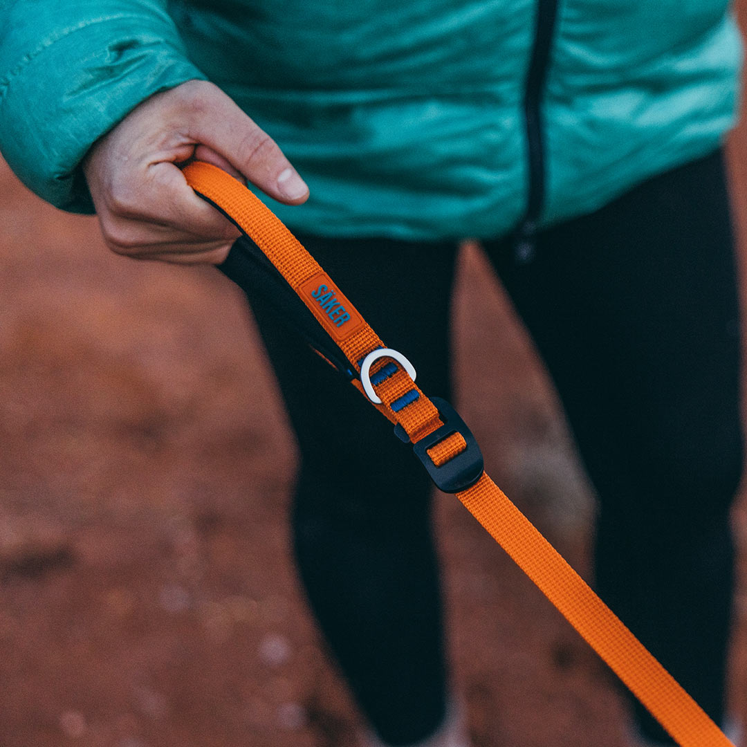 Close view of a woman holding the orange canyon leash in her finger bones