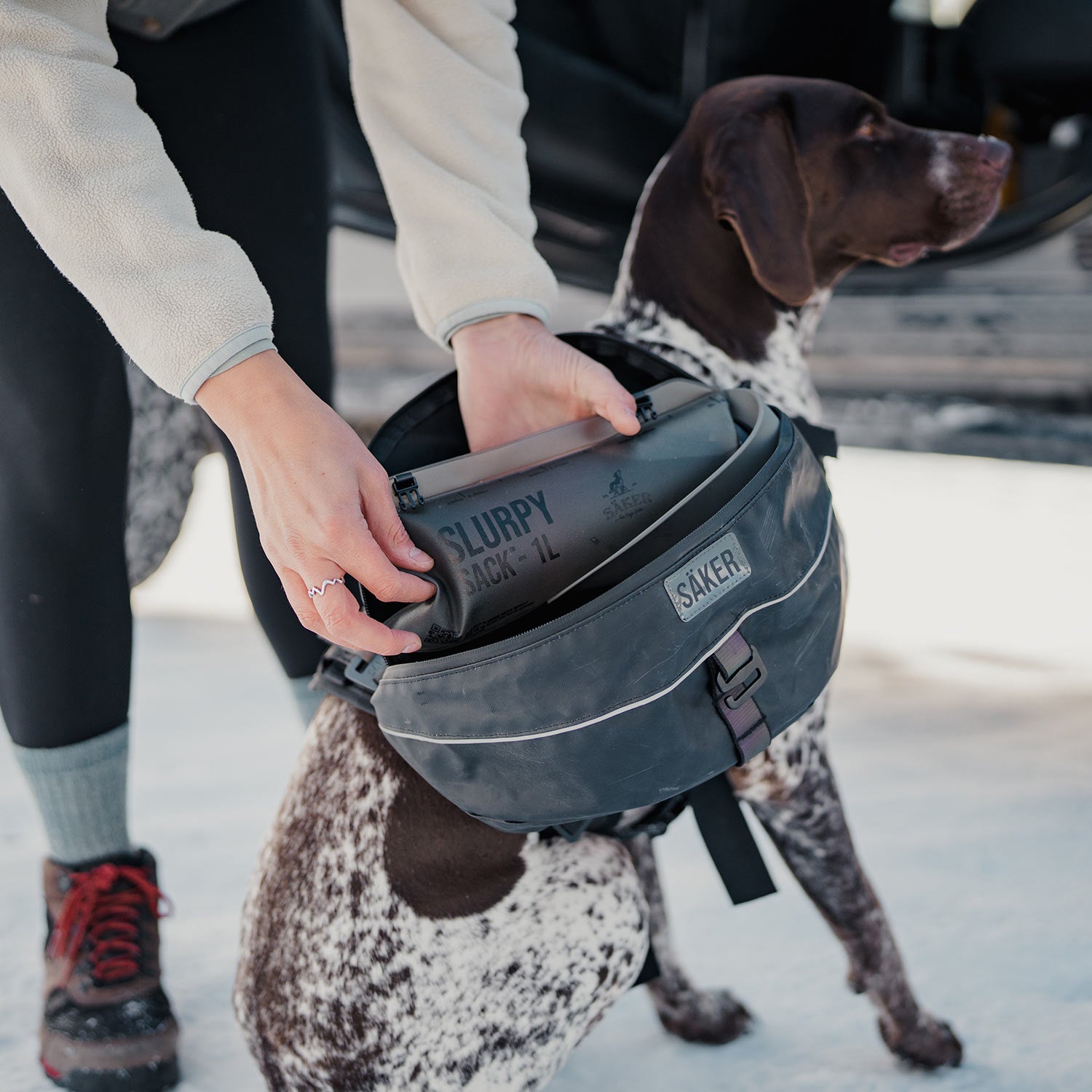 Woman loading the pouch of her dog ascension dog pack
