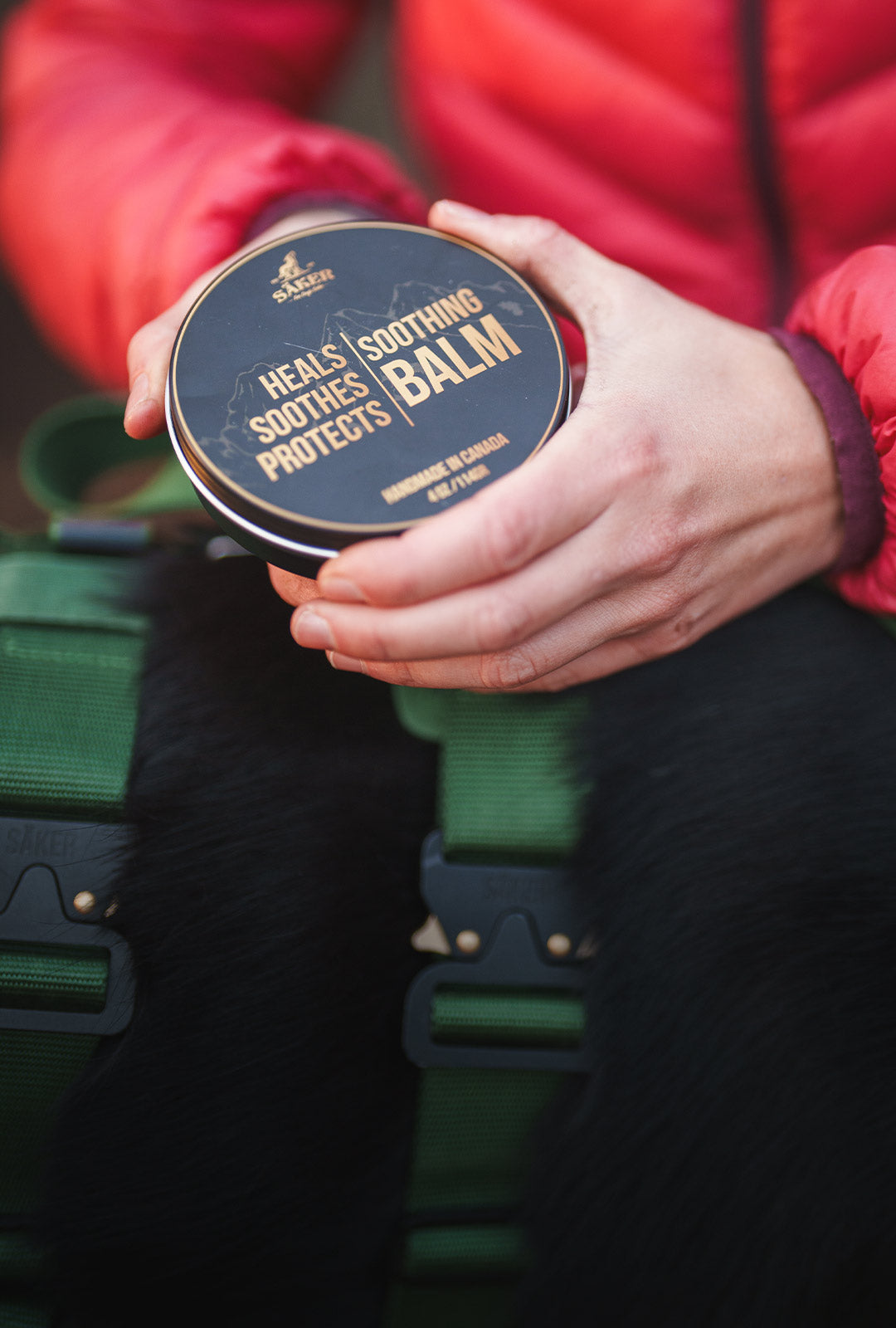 woman opening a tin can of soothing balm from saker before applying it to her dog paws