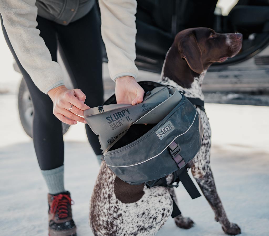 Woman installing the slurpy sack inside the right pouch of the Ascension Dog Pack in grand teton national park