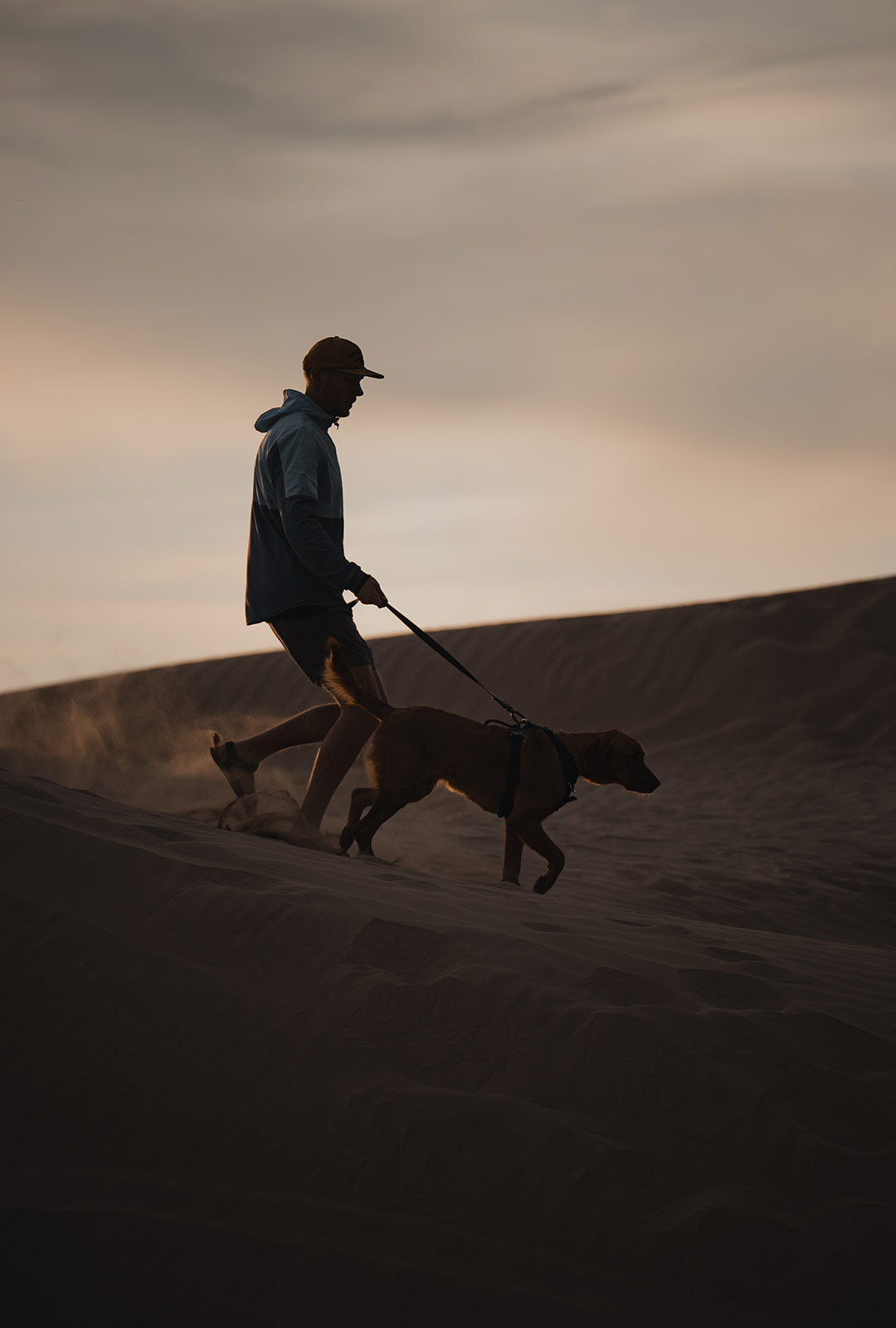 Silhouette of a man and his dog in the desert dunes of little sahara