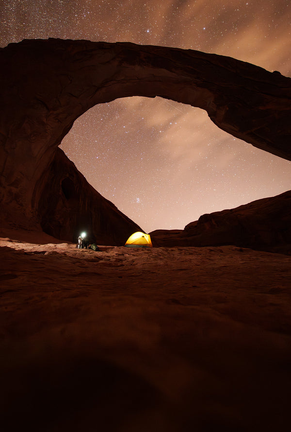 Tent setup underneath an arch in Moab with a sky full of stars. A dog and his mom near their tent with Säker gear