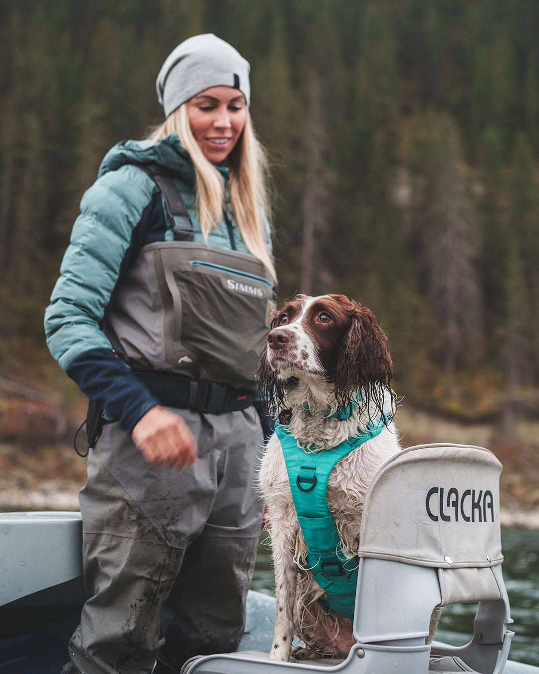 Paula Shearer and her dog Willow in the boat. Her dog is wearing the Saker Muse harness in Skeena Teal