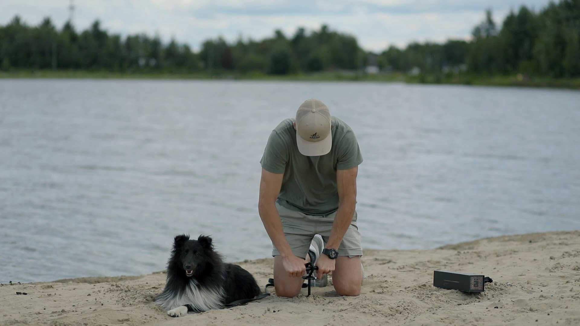 Saker founder installing the gravity dog tie out stake in the sand at the beach